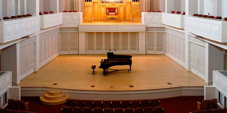 Image from inside Auer Hall, the stage sits above the center audience and is surrounded by balcony seating. The Seward organ is visible starting on the second floor. 