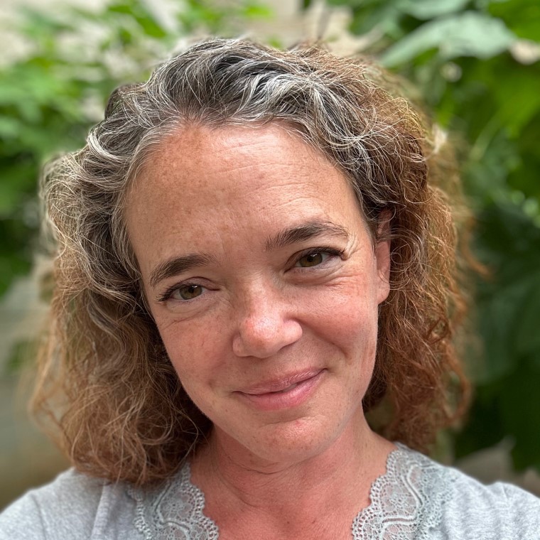 Woman smiling with blurred greenery in the background