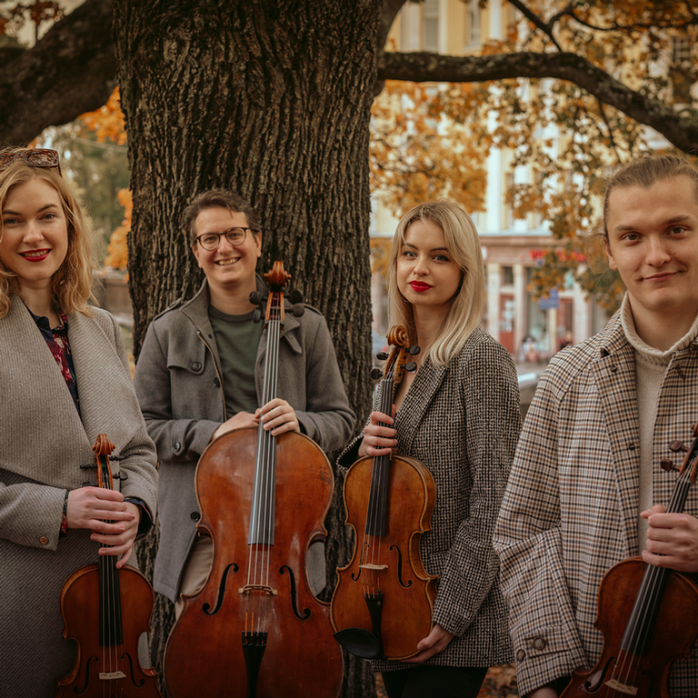 a quartet smiling and holding their instruments