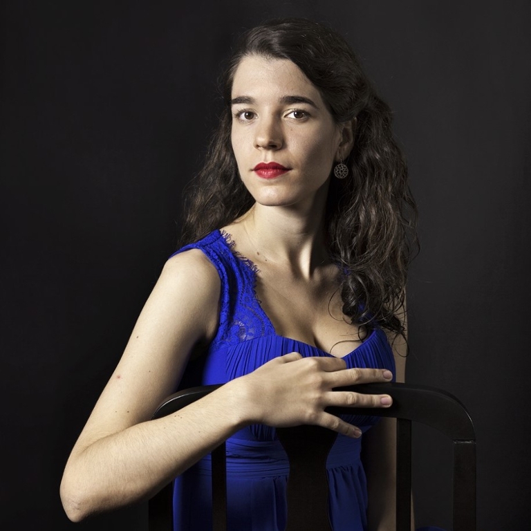 Woman in a blue dress sitting on a backwards-facing chair.